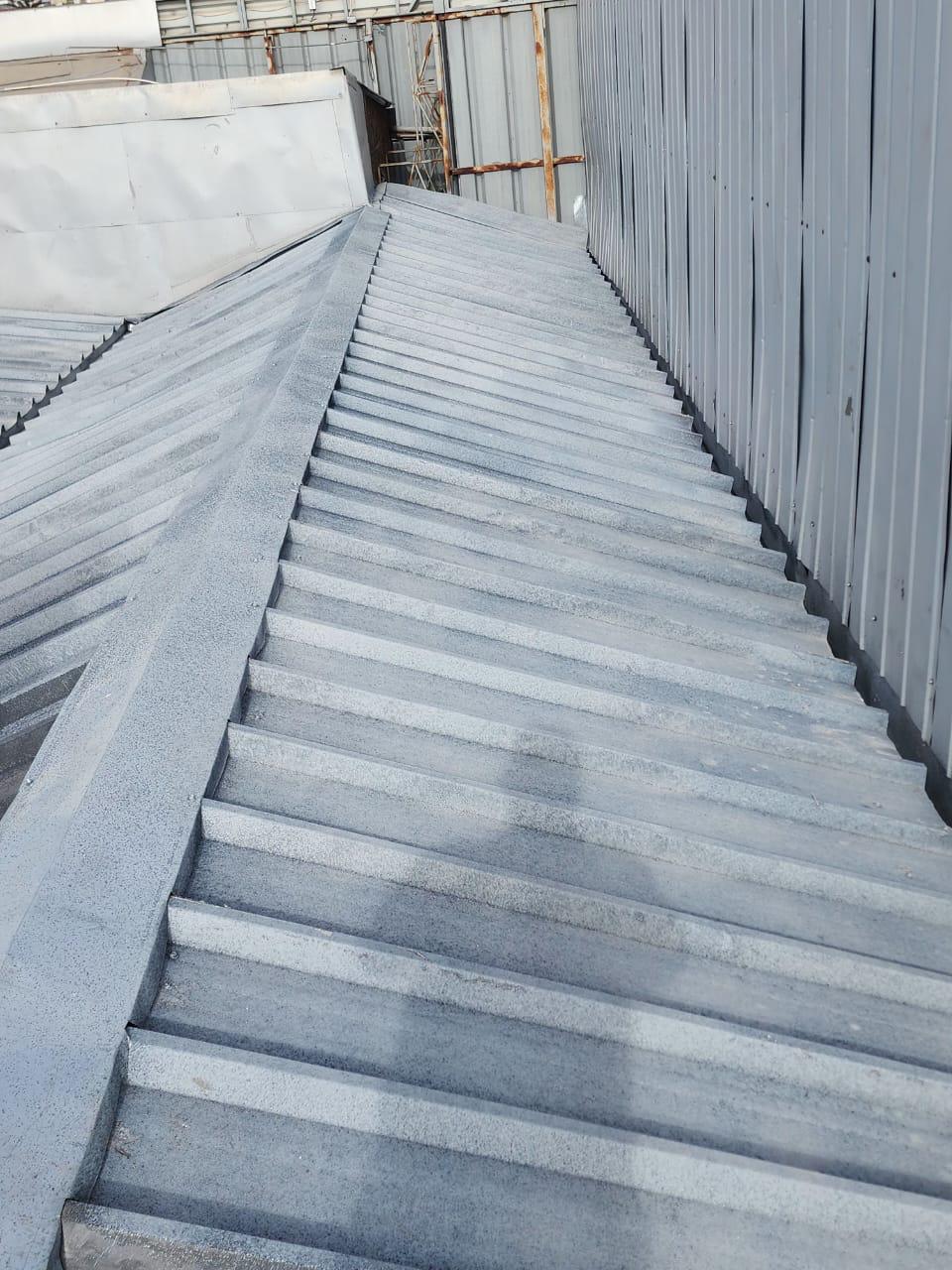 Trabajador aplicando membrana negra en cubierta plana